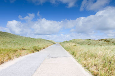 Empty road passing through grassy field