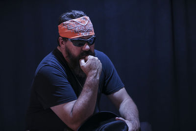 Midsection of man wearing sunglasses sitting against black background