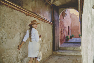 Rear view of young woman standing against wall