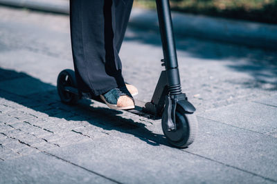 Low section of woman on push scooter at road