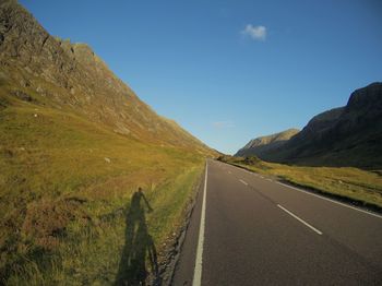 Road leading towards mountains against sky