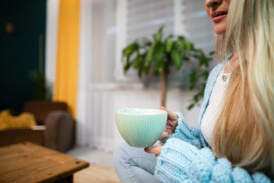 A mug of hot coffee in a woman's hands at home.