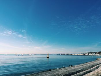 A pure invitation to a journey. from the beach, looking at sailboats and the horizon on a sunny day