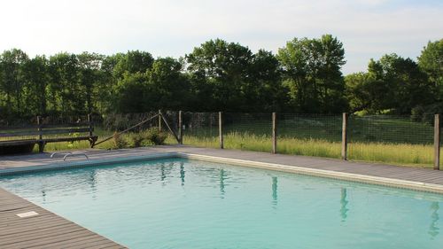 Swimming pool by trees against sky