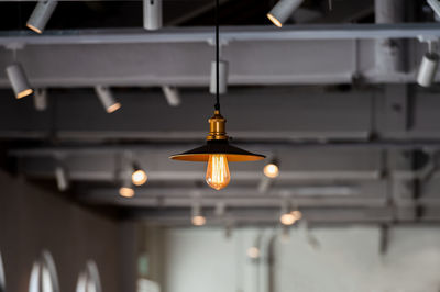 Low angle view of illuminated light bulb indoors