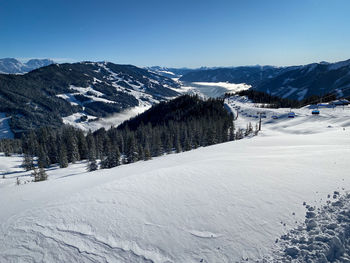 Scenic view of snow covered mountains in saalbach hinterglemm in the austrian alps against blue sky