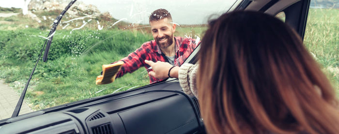 Man cleaning windshield of car