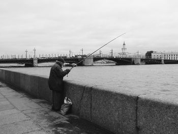 Rear view of man walking on bridge against sky