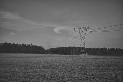 Electricity pylon on field against sky during winter