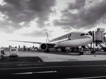 Airplane on airport runway against sky