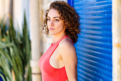 Portrait of young woman standing against wall