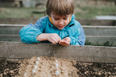 Spring planting seeding farm garden. little kid boy farmer gardener plants sow vegetable seeds soil