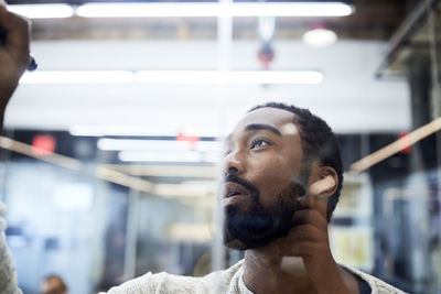 Close-up of young businessman writing on glass while planning in meeting at board room