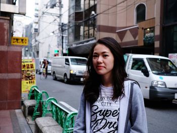 Beautiful young woman standing on street in city