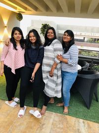 Full length portrait of smiling young women standing outdoors