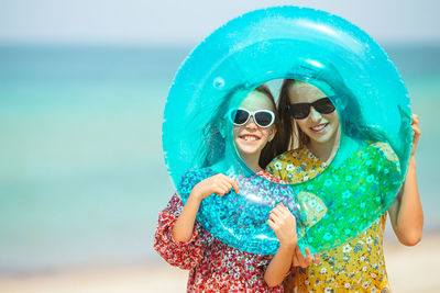 Portrait of girls holding inflatable ring at beach