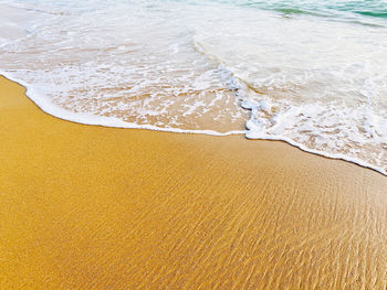 Beach sand sea water summer background. white foam wave sandy seashore top view.