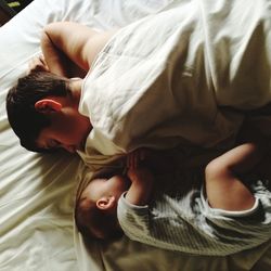 High angle view of baby sleeping with mother on bed at home