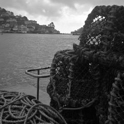 Close-up of fishing net at harbor against sky