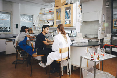 Multi-ethnic young university students sitting on chairs in chemistry laboratory