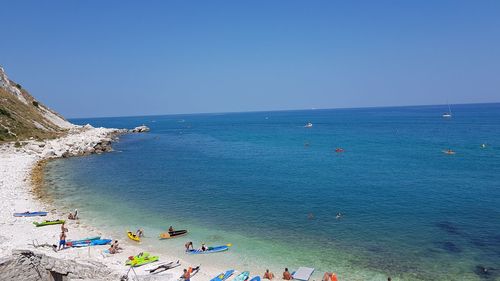 High angle view of people on beach against clear blue sky
