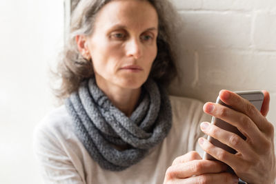 Woman using smart phone while leaning by window