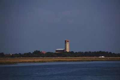 Lighthouse by sea against clear sky