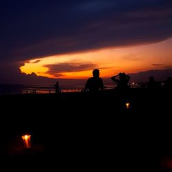 Silhouette people by sea against sky at night