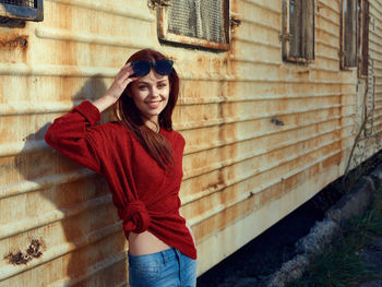 Portrait of young woman standing against building