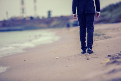 Low section of man standing on beach