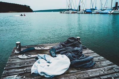 Boats moored on pier by river against sky