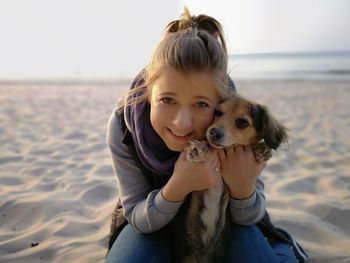 Portrait of woman embracing dog at beach