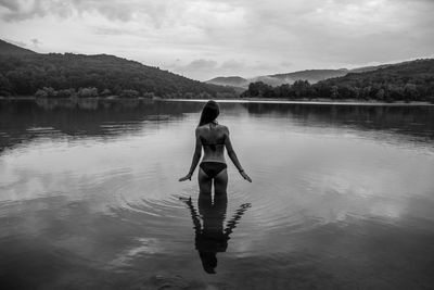 Rear view of man standing in lake against sky