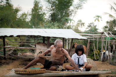 People sitting on sidewalk against trees