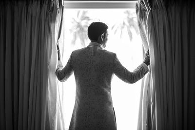 Rear view of man and woman standing by window
