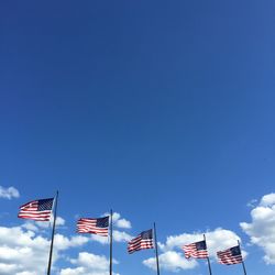 Low angle view of american flags against blue sky