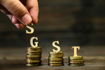 Cropped hand with gst text on stacked coins at table