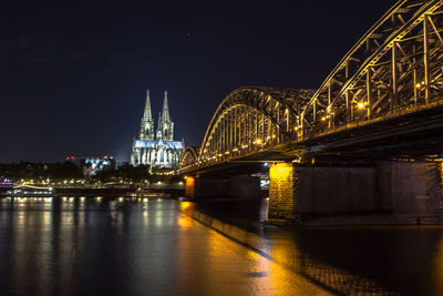 Illuminated bridge over river at night