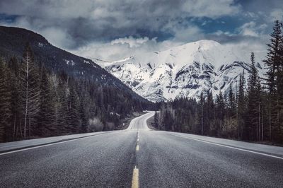 Road by mountains against sky during winter