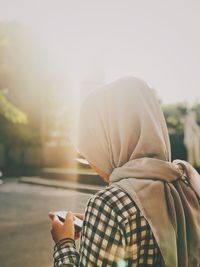 Rear view of woman using mobile phone outdoors