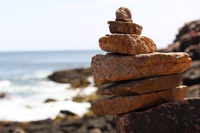 Close-up of stack of rocks on beach against sky