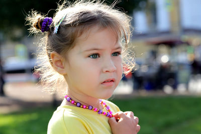 She rubs a little blonde girl in a yellow blouse close-up on the street on a sunny afternoon