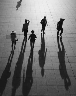 High angle view of people walking with long shadows on footpath in city