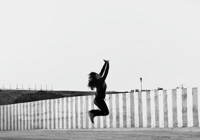 Full length of woman jumping against clear sky