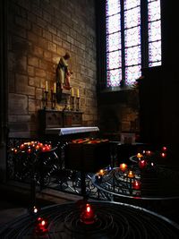 Statue against illuminated window