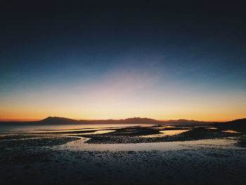 Scenic view of beach against clear sky during sunset