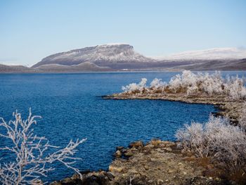 Scenic view of lake and mountains against clear blue sky