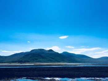 Scenic view of lake and mountains against blue sky