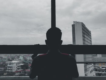 Rear view of man standing by buildings against sky