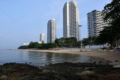 City buildings by sea against sky